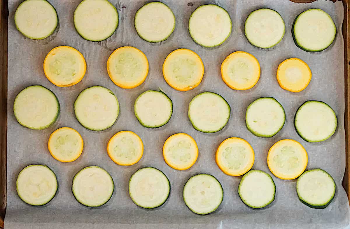 sliced yellow and green squash on a baking sheet