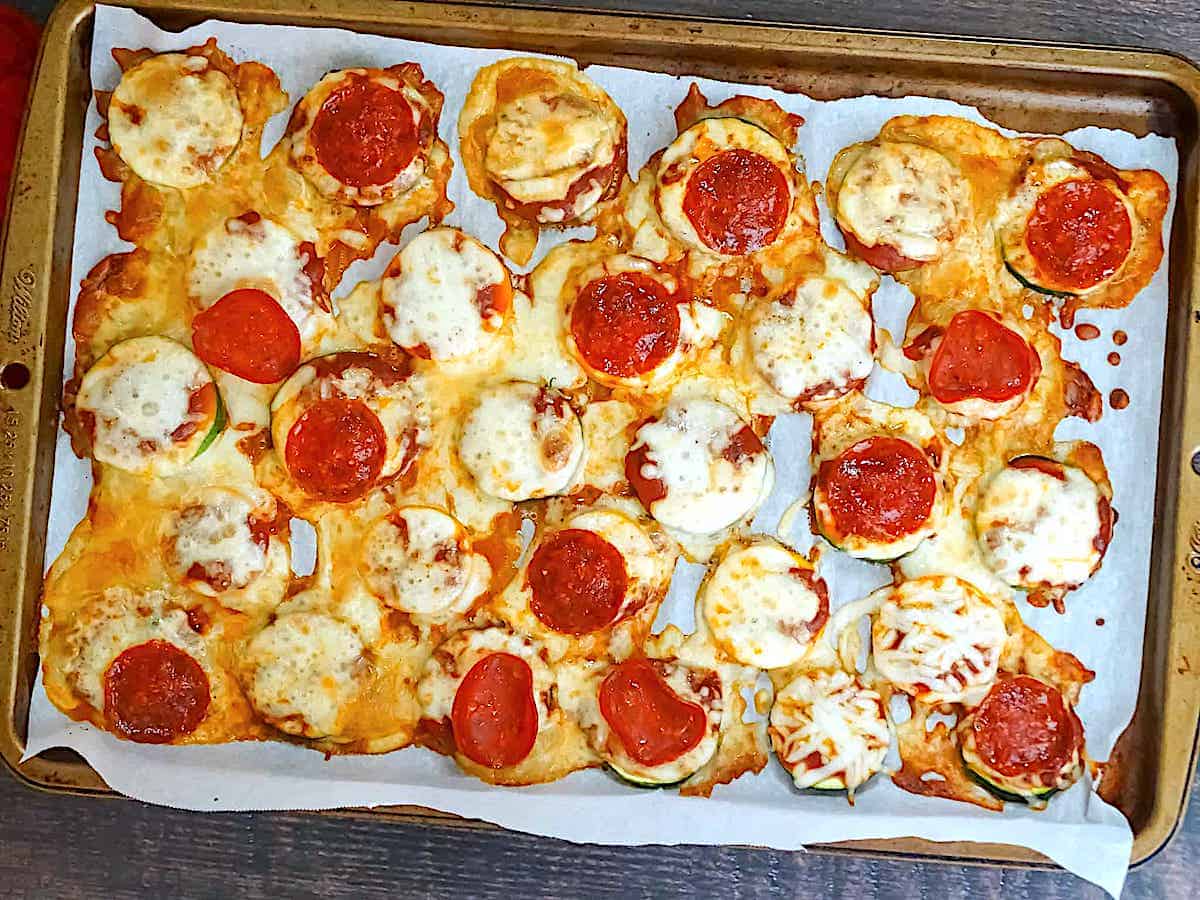 zucchini slices baked with mozzarella and pepperoni on a baking sheet