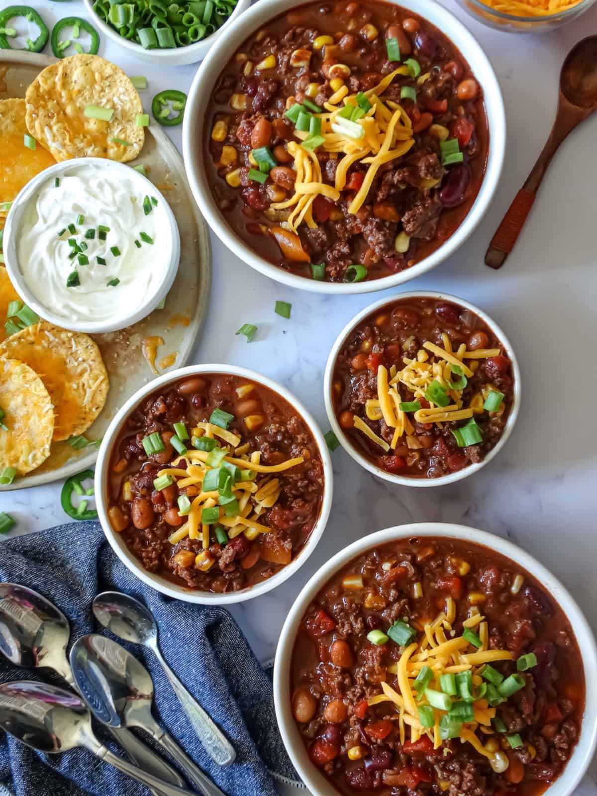 instant pot chili in bowls topped with cheddar cheese, scallions and tortilla chips