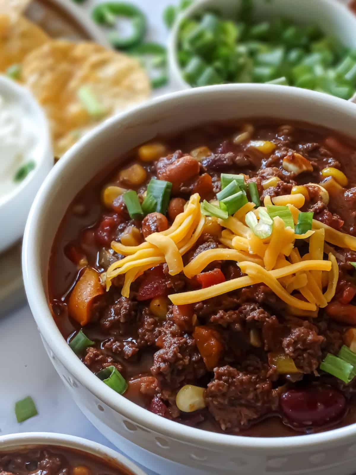 close up of pressure cooked chili in a white bowl topped with cheese