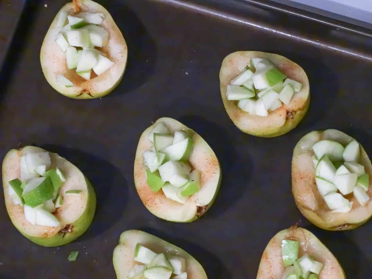 pears filled with apples and sprinkled with cinnamon sugar on a baking sheet