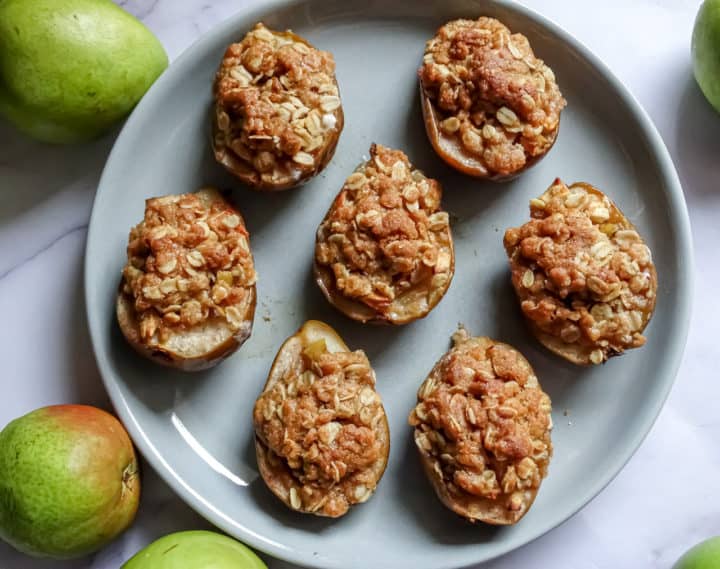 baked pears with apple crisp topping on a grey plate