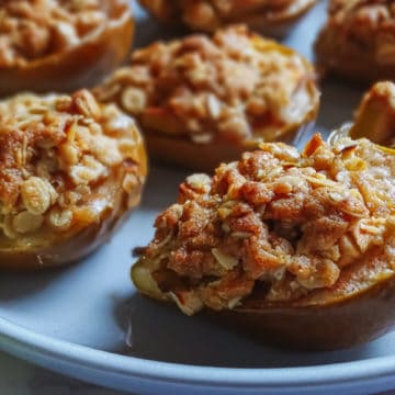 baked pears filled with apple crisp topping on a grey plate