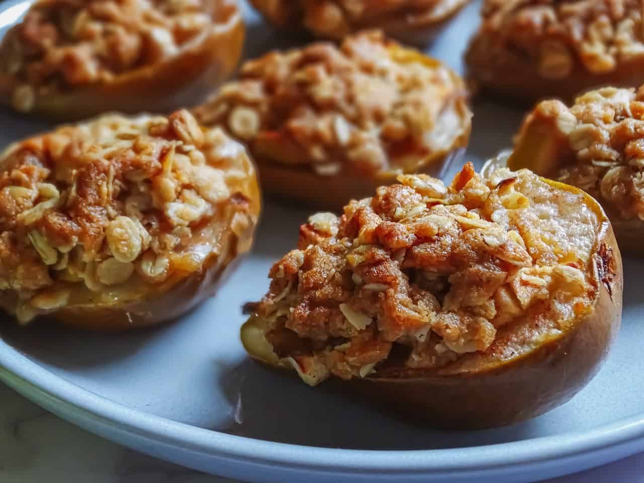 baked pears filled with apple crisp topping on a grey plate