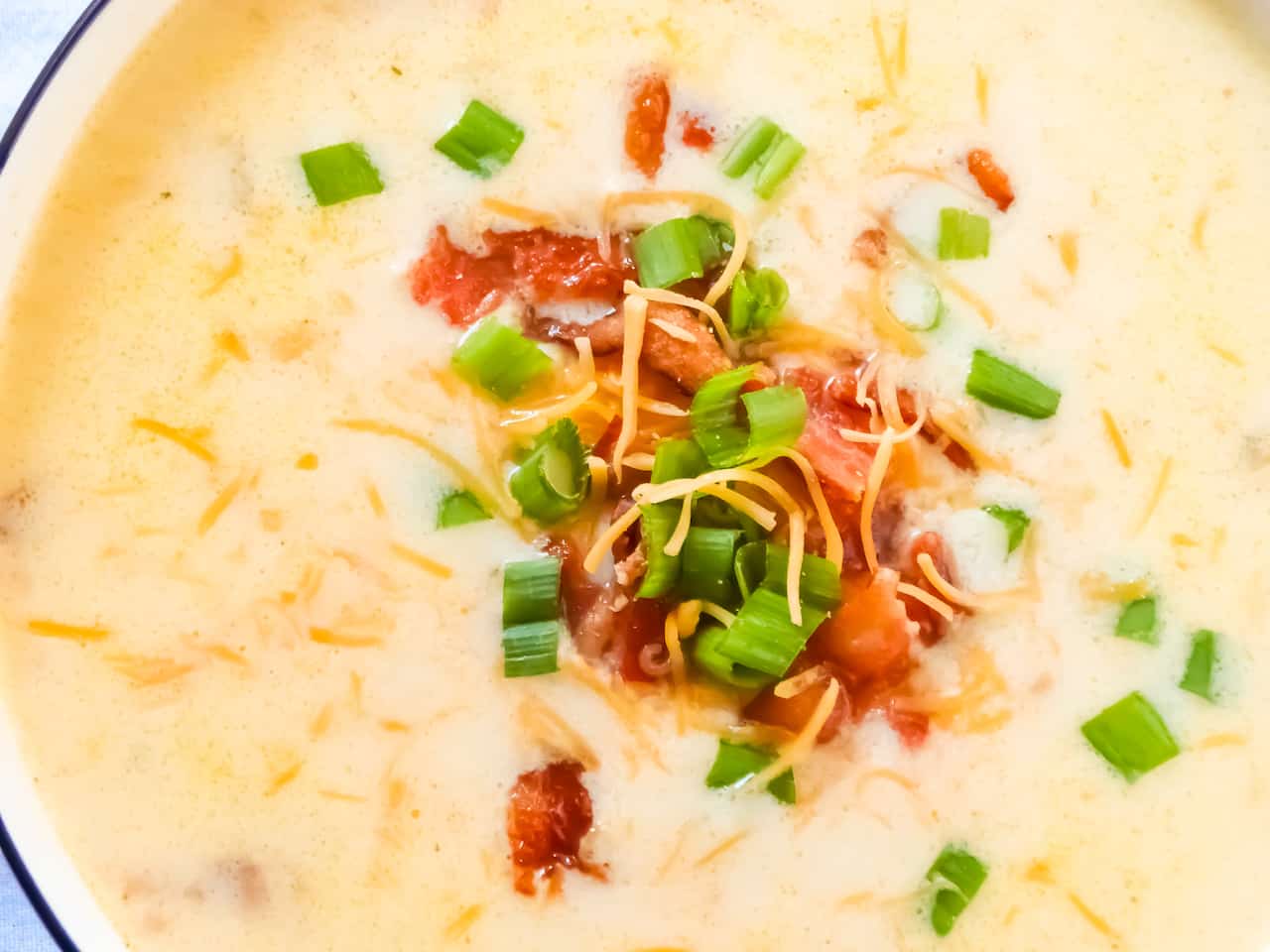 slow cooker loaded potato soup topped with chives, bacon and cheddar cheese
