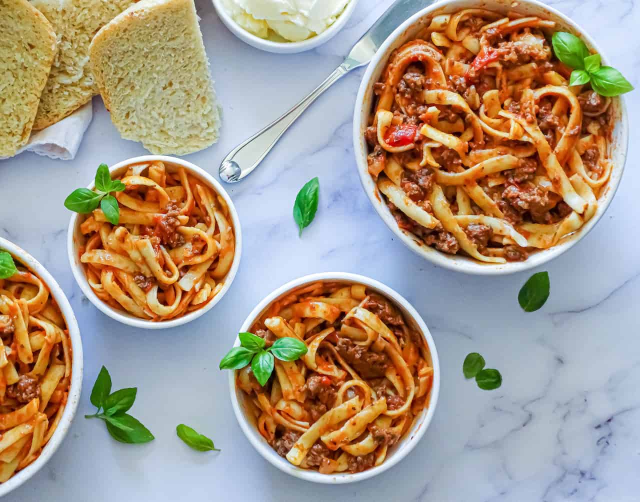 instant pot spaghetti in 4 serving bowls with garlic bread