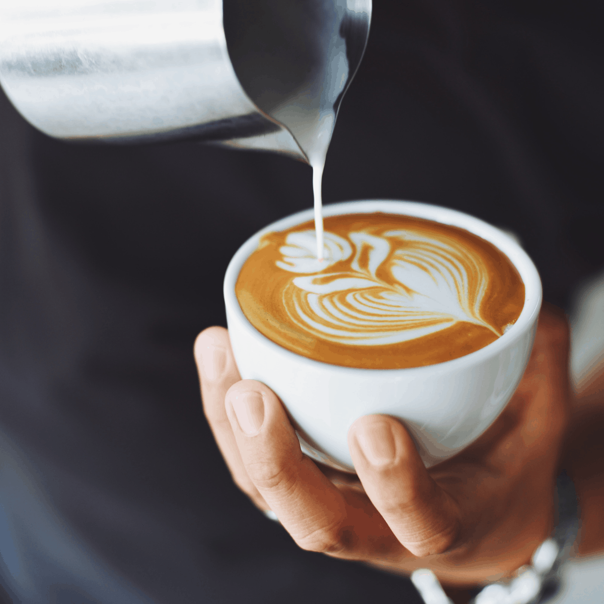 milk being poured into a coffee cup