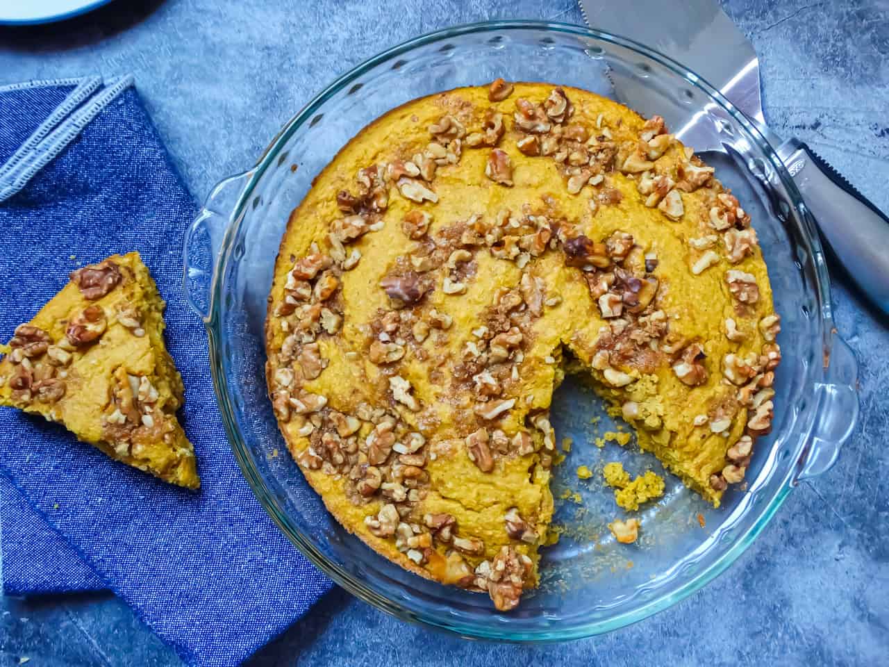 pumpkin cornbread with walnut topping on a grey background, sliced on a blue cloth