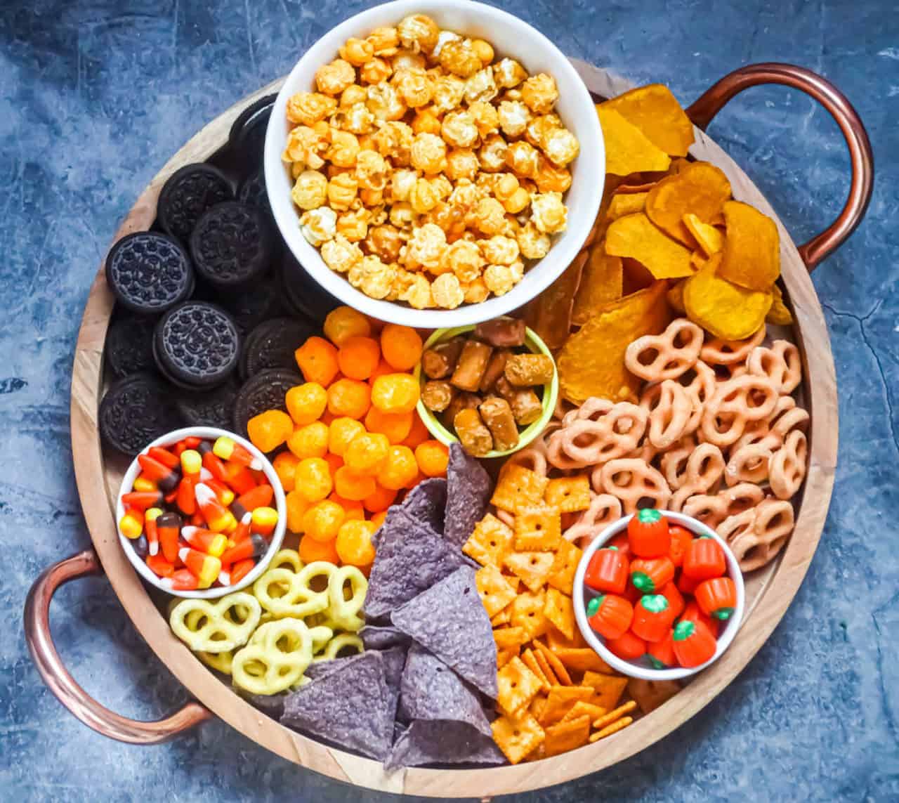 a sweet and salty halloween board with orange, black, and yellow snacks