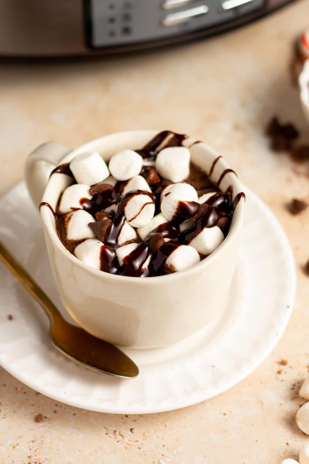 crock pot hot chocolate in a cup with marshmallows and chocolate syrup