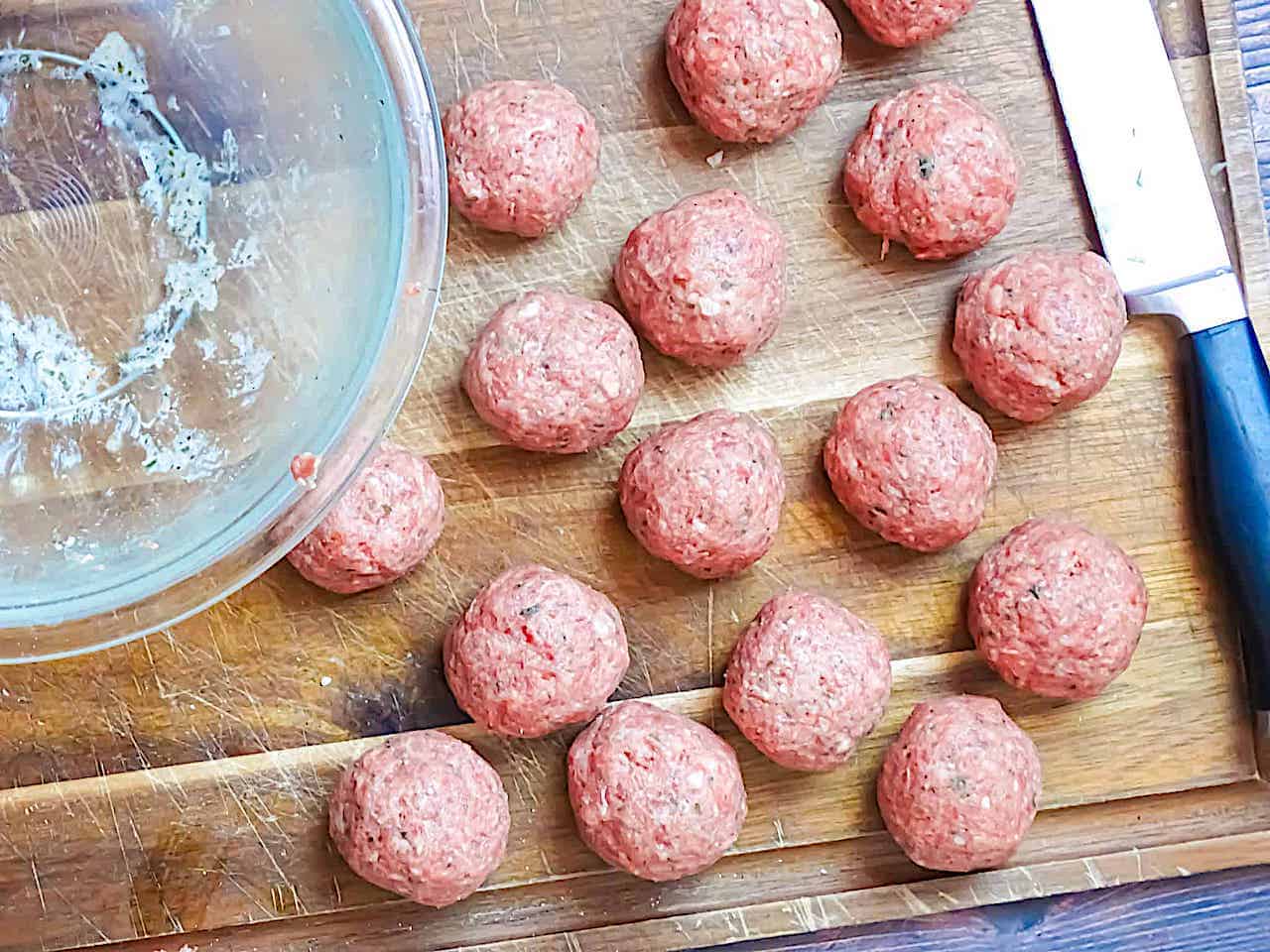 uncooked meatballs rolled into balls on a cutting board