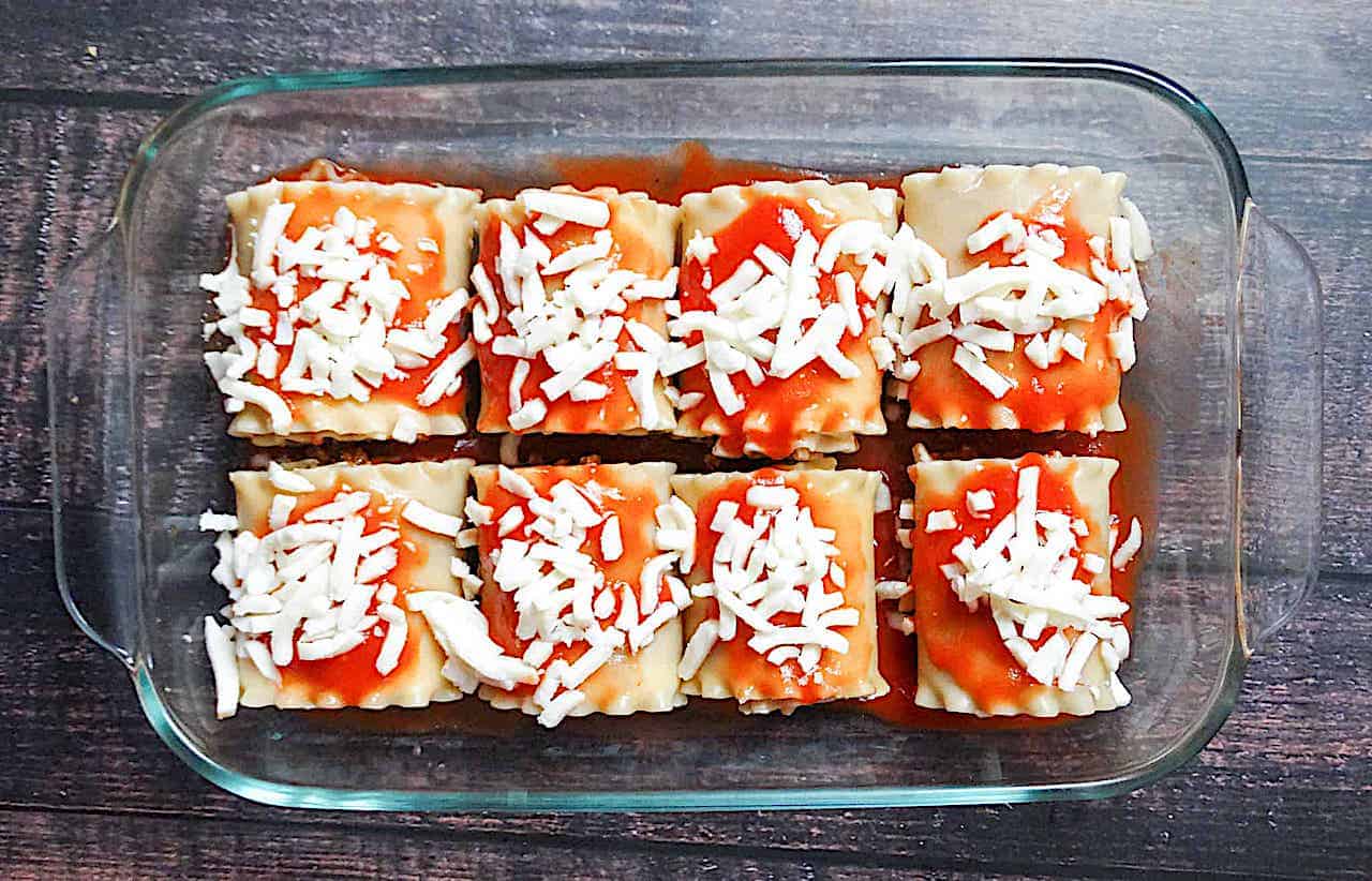 uncooked lasagna roll ups topped with mozzarella cheese and tomato sauce