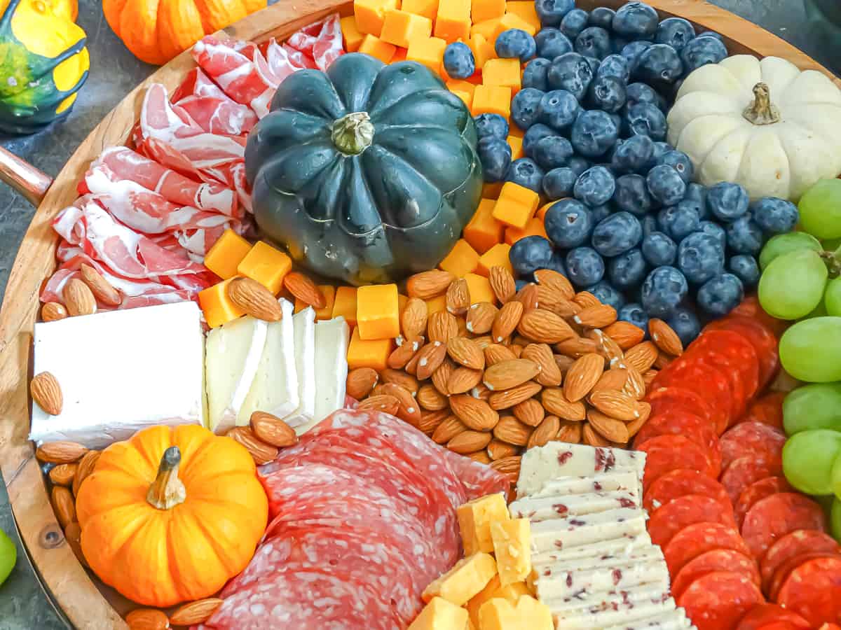 Meats, cheeses, fruits, nuts, and spreads arranged on a circular board intended to be an easy Thanksgiving appetizer