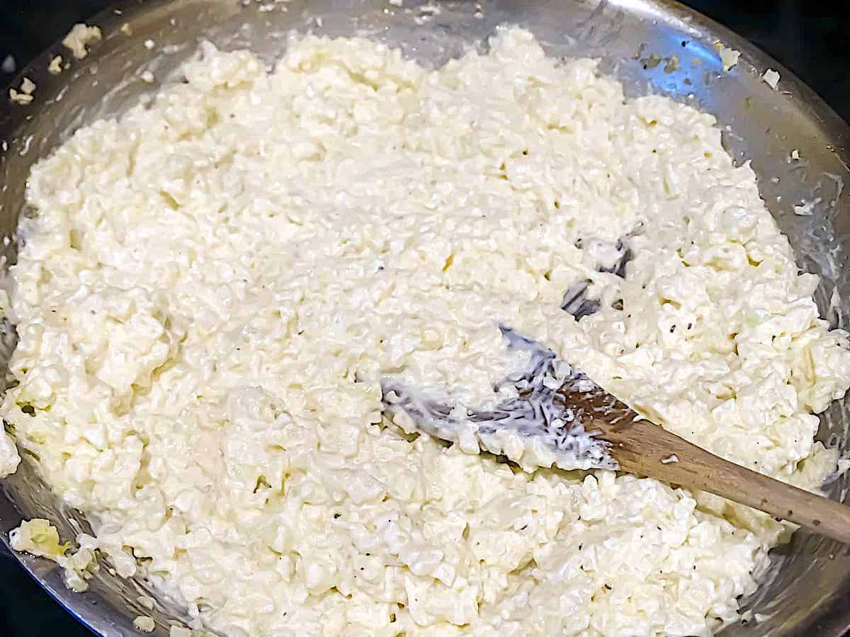 cauliflower rice mixed with cream cheese and sour cream in a pan