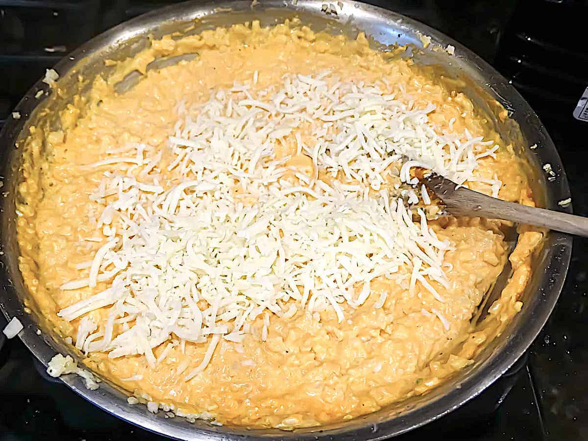 cauliflower rice mixed with buffalo sauce, cream cheese, sour cream, and mozzarella in a pan