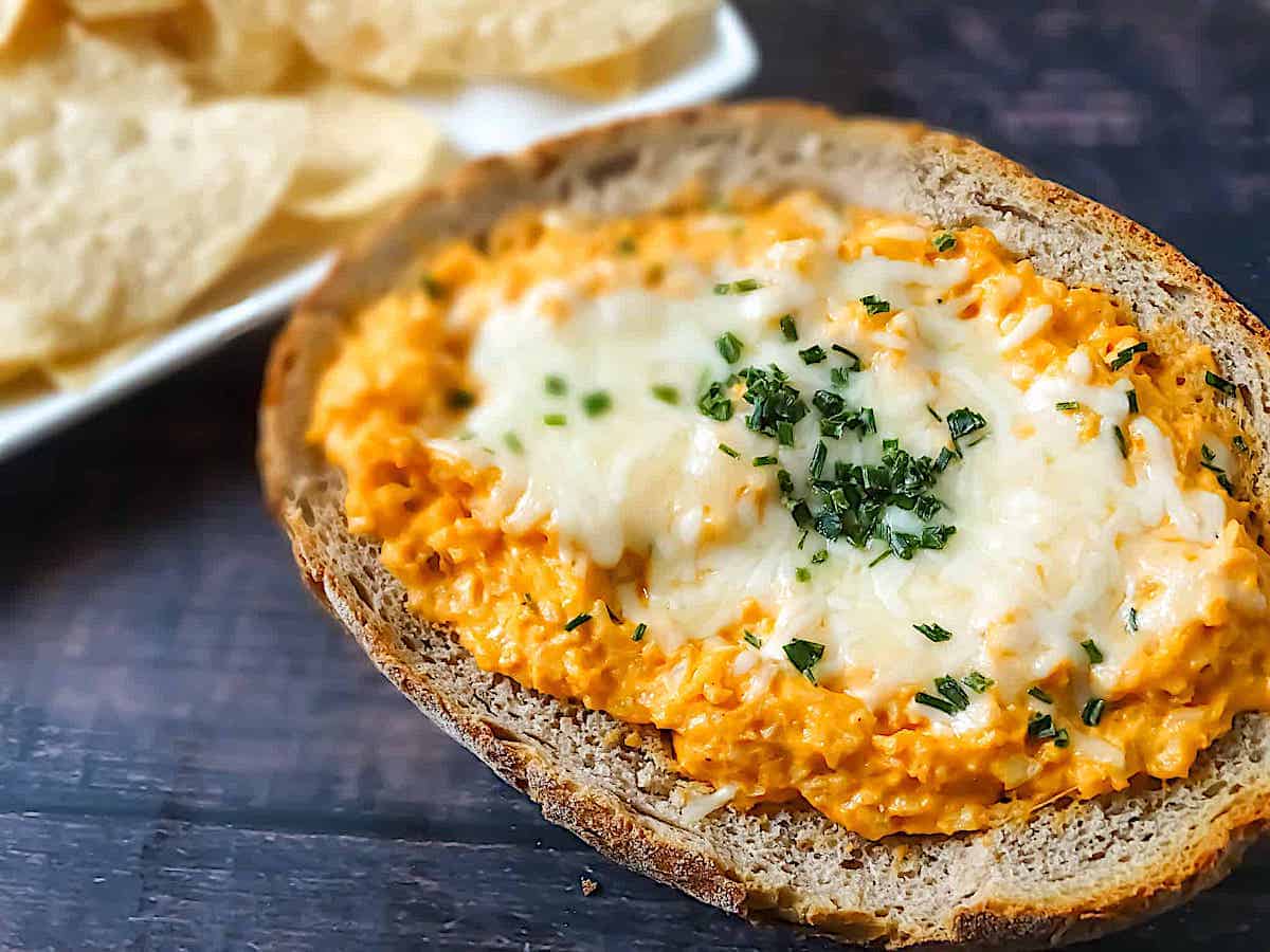 buffalo cauliflower dip in a bread bowl, topped with mozzarella and chives