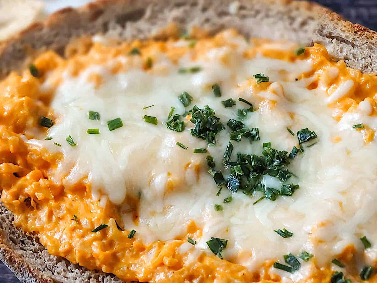 buffalo cauliflower dip in a bread bowl, topped with mozzarella and chives