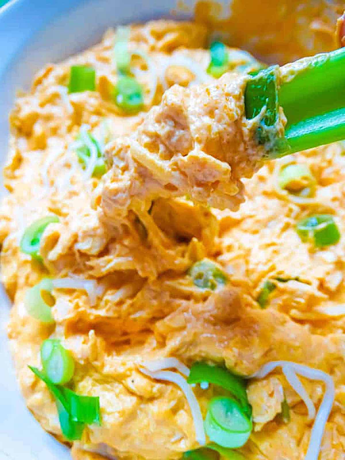 buffalo chicken dip in a serving bowl garnished with chives and with celery dippers
