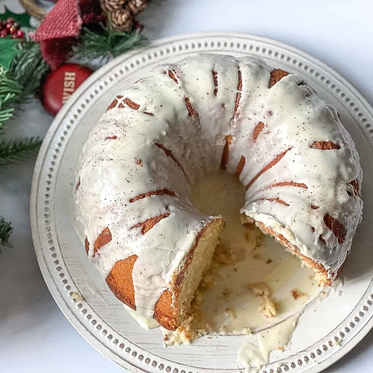 sliced eggnog cake glazed with icing and topped with nutmeg on a white plate