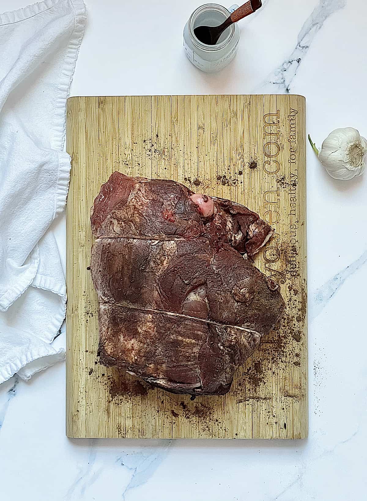 bone in leg of lamb on a cutting board rubbed with spiced