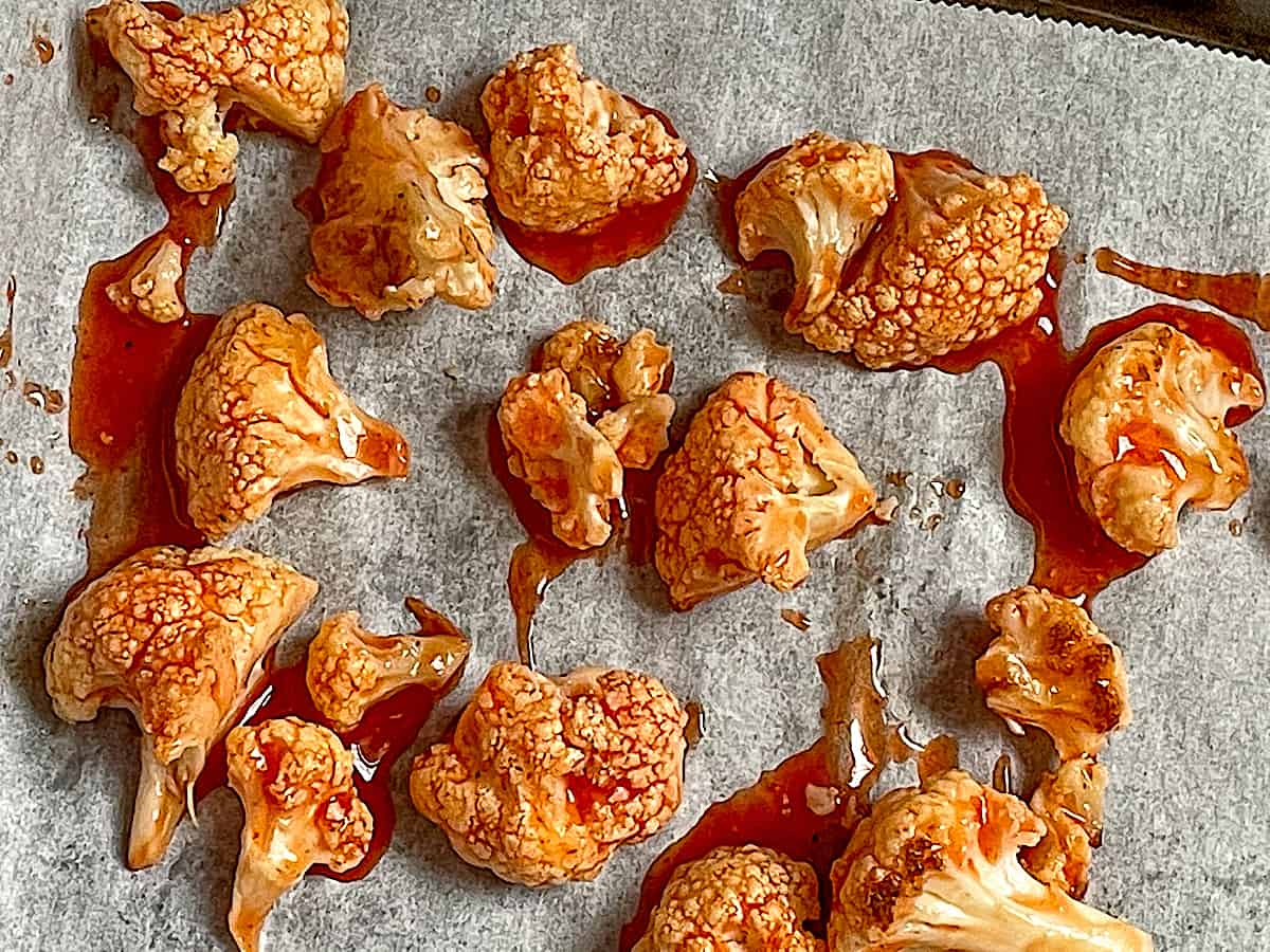 cauliflower on a baking sheet tossed with buffalo sauce