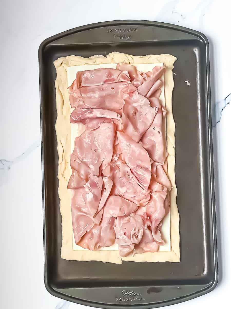 croissant dough topped with sliced cheese and ham