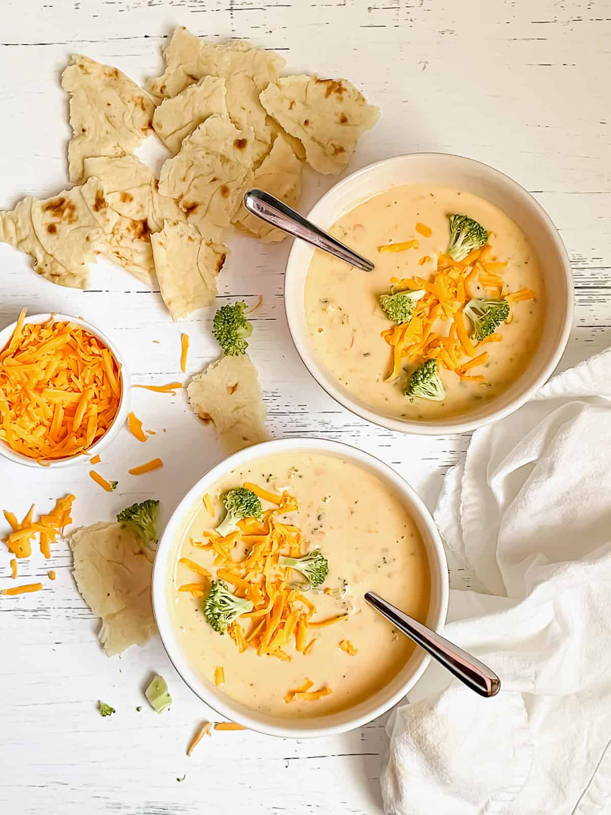 2 bowls of creamy instant pot broccoli cheddar soup, topped with extra broccoli and cheese