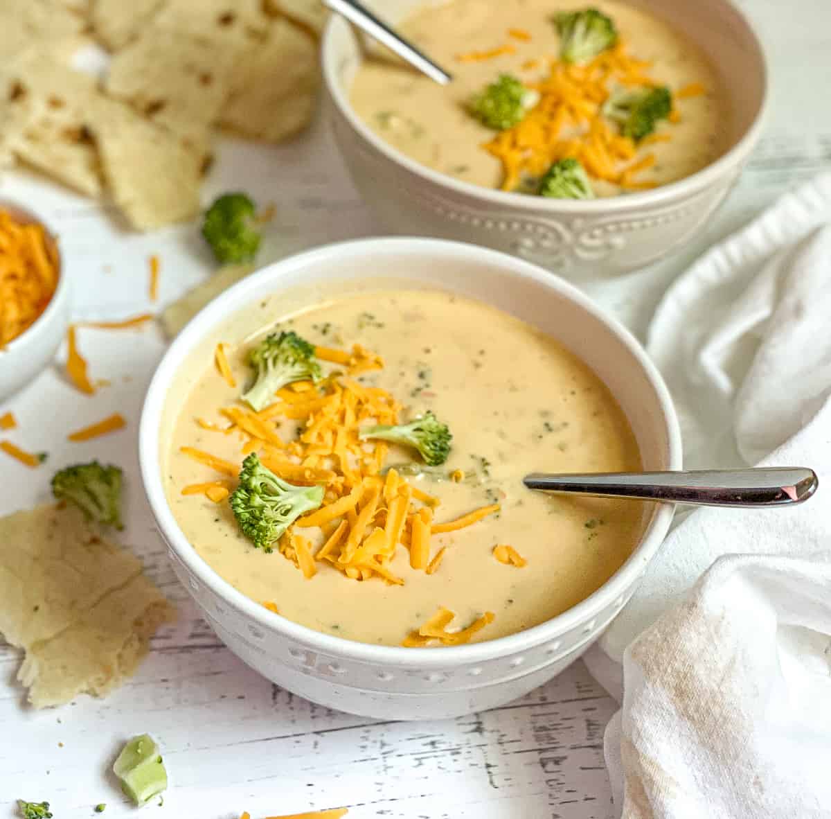 2 bowls of creamy instant pot broccoli cheddar soup, topped with extra broccoli and cheese