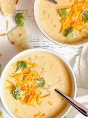2 bowls of creamy instant pot broccoli cheddar soup, topped with extra broccoli and cheese