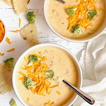 2 bowls of creamy instant pot broccoli cheddar soup, topped with extra broccoli and cheese