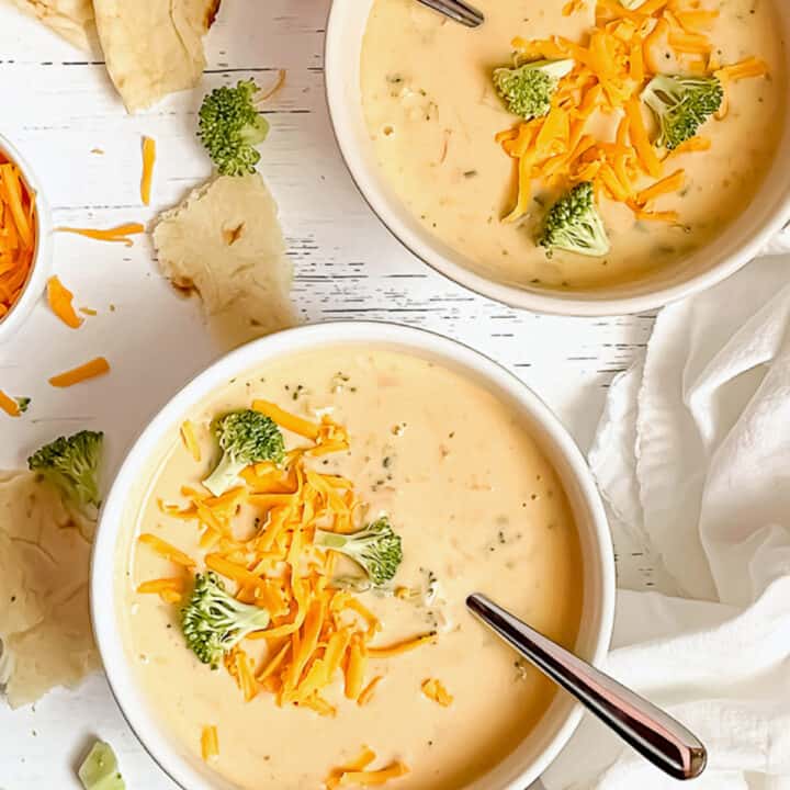 2 bowls of creamy instant pot broccoli cheddar soup, topped with extra broccoli and cheese