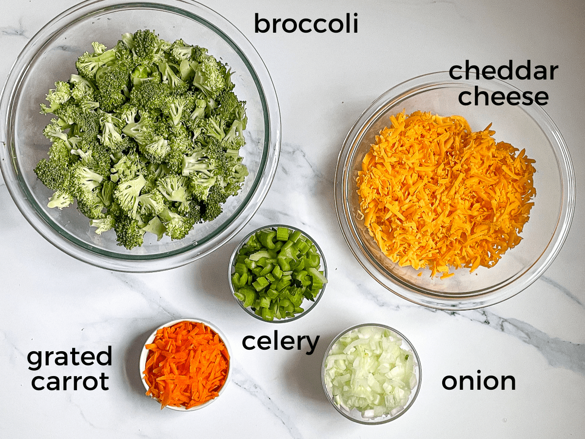 cheddar cheese, broccoli, celery, onion, and carrot on a white background