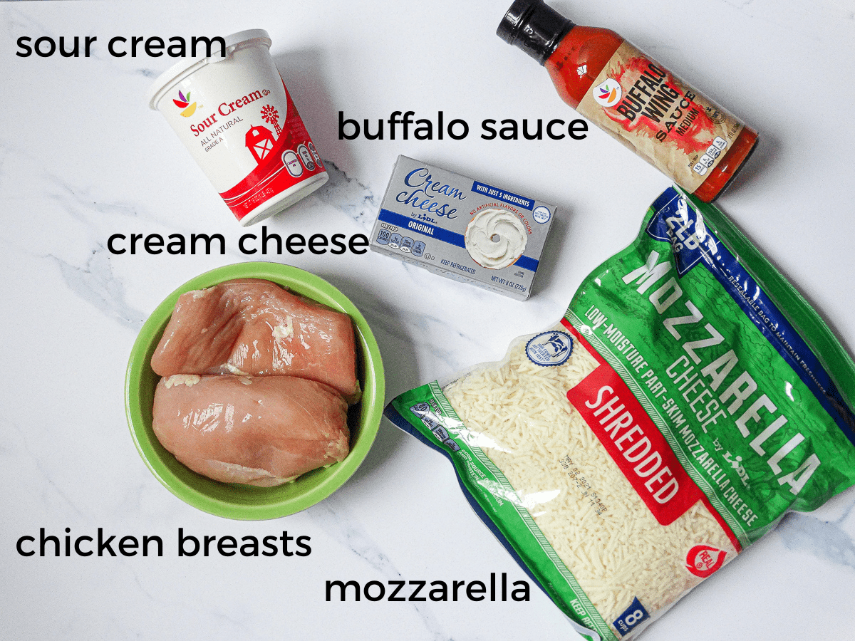 buffalo sauce, mozzarella, sour cream, cream cheese, and chicken breasts on a white background