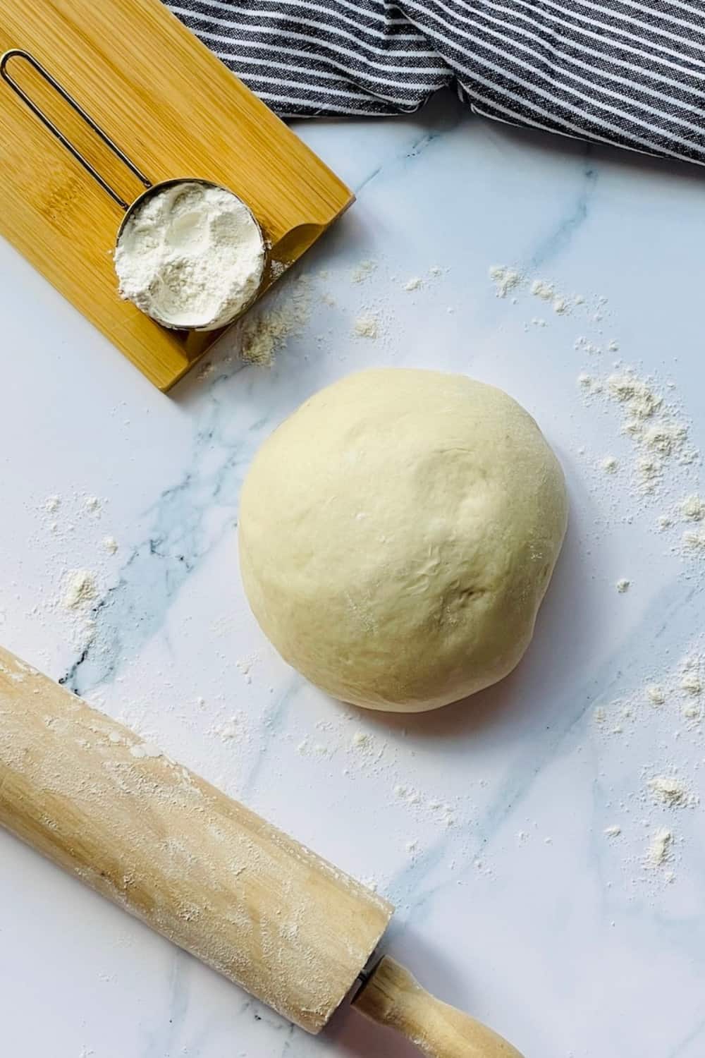 pizza dough ball rising on a white surface