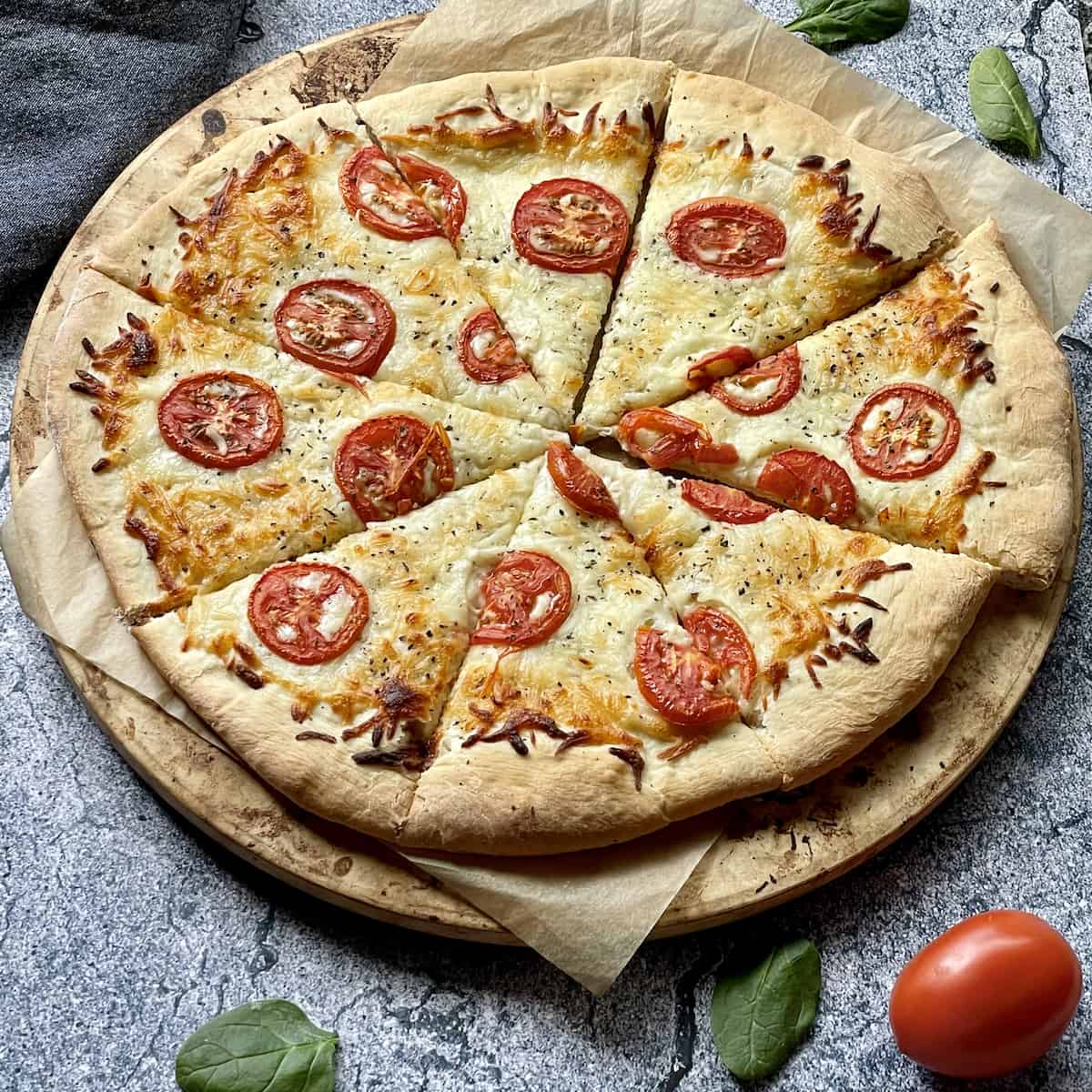 white pizza topped with tomatoes and basil on a grey background