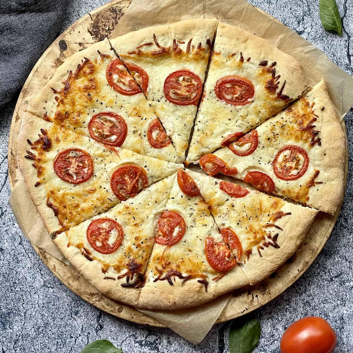 white pizza sliced on a pizza stone on a grey background