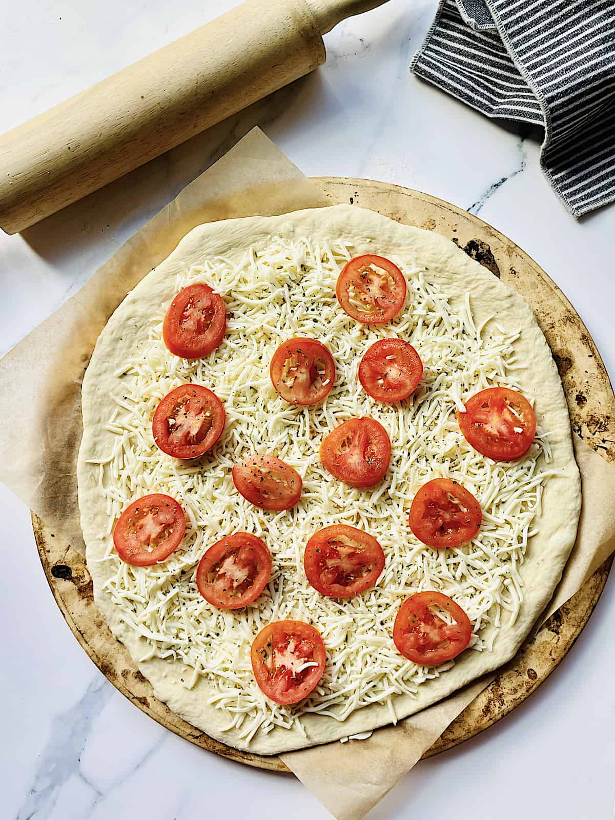 pizza dough on a pizza pan topped with mozzarella cheese and tomatoes