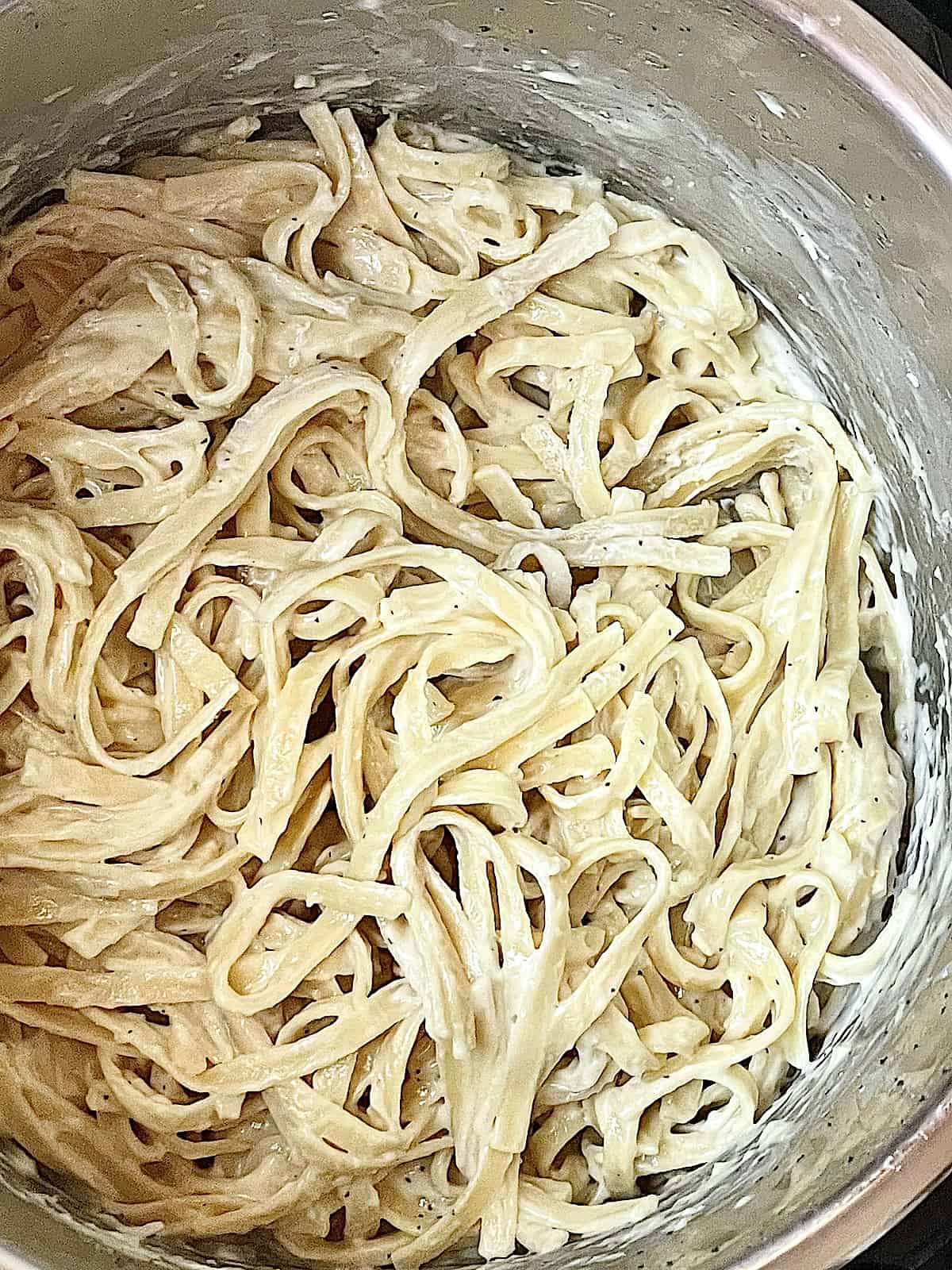 noodles in an instant pot mixed with heavy cream and parmesan cheese