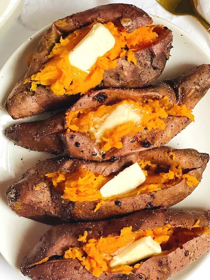 air fryer sweet potatoes on a white plate topped with butter