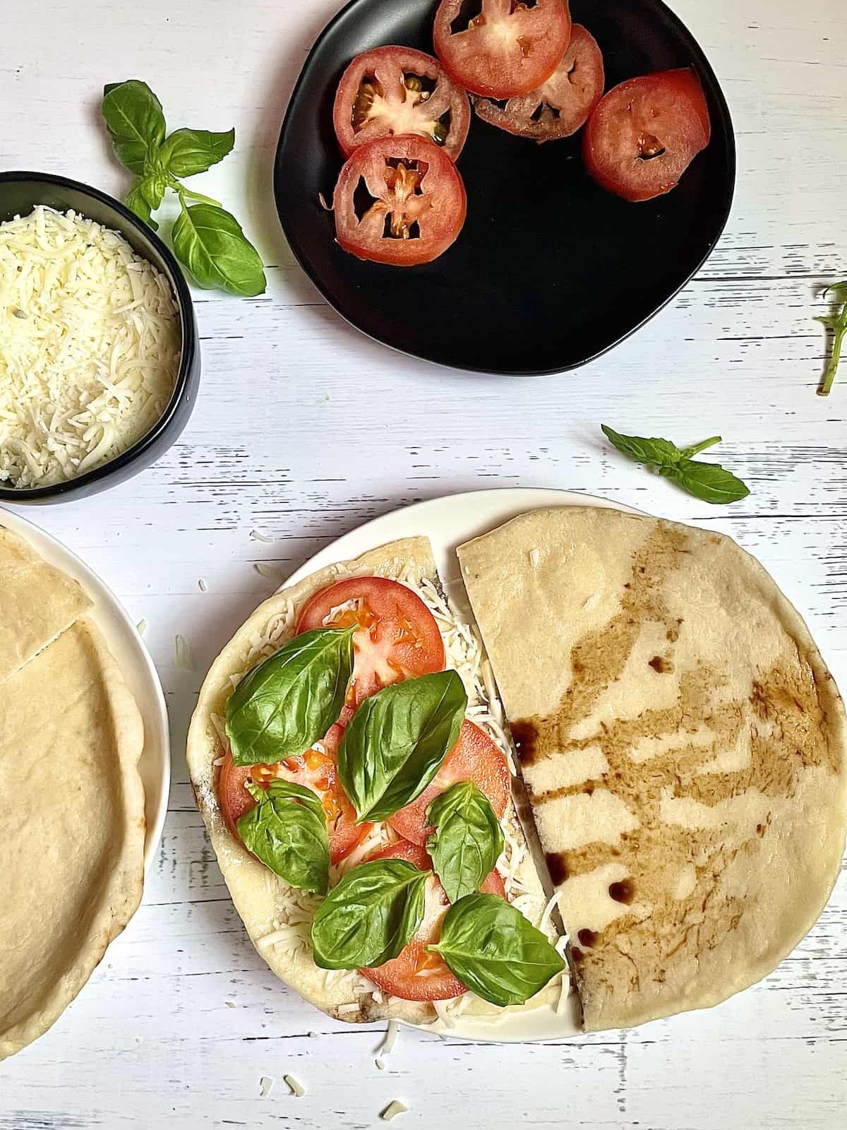 naan bread covered with cheese, tomatoes, and basil