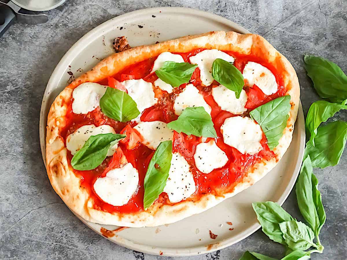 homemade margarita pizza topped with fresh basil leaves