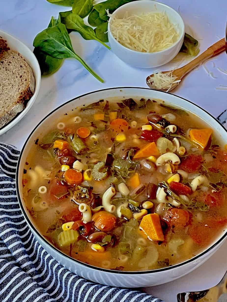 minestrone soup in a bowl with bread and parmesan cheese