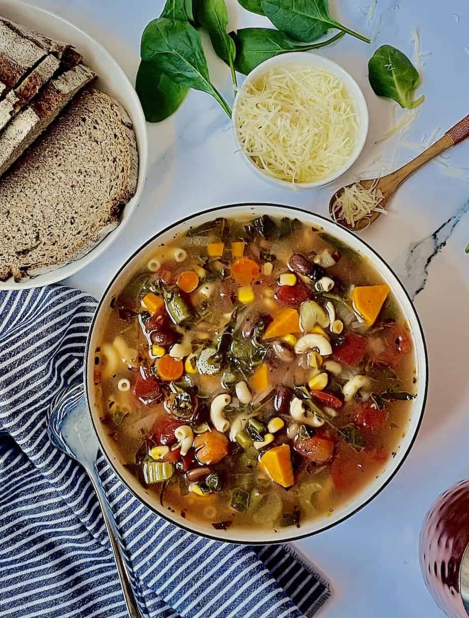 instant pot minestrone soup in a white bowl with parmesan cheese and bread 