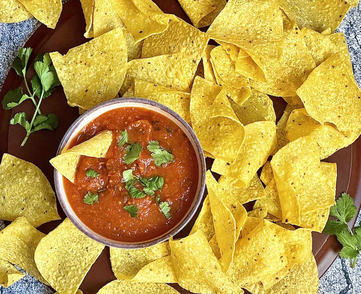 Salsa roja in a bowl surrounded by chips for dipping
