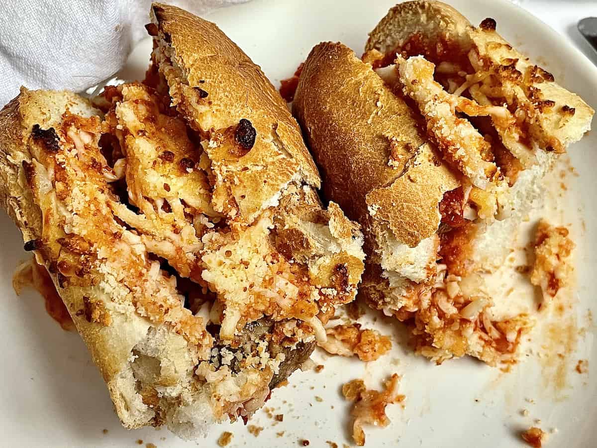 air fryer meatball parmesan sub cut into two pieces on a white plate