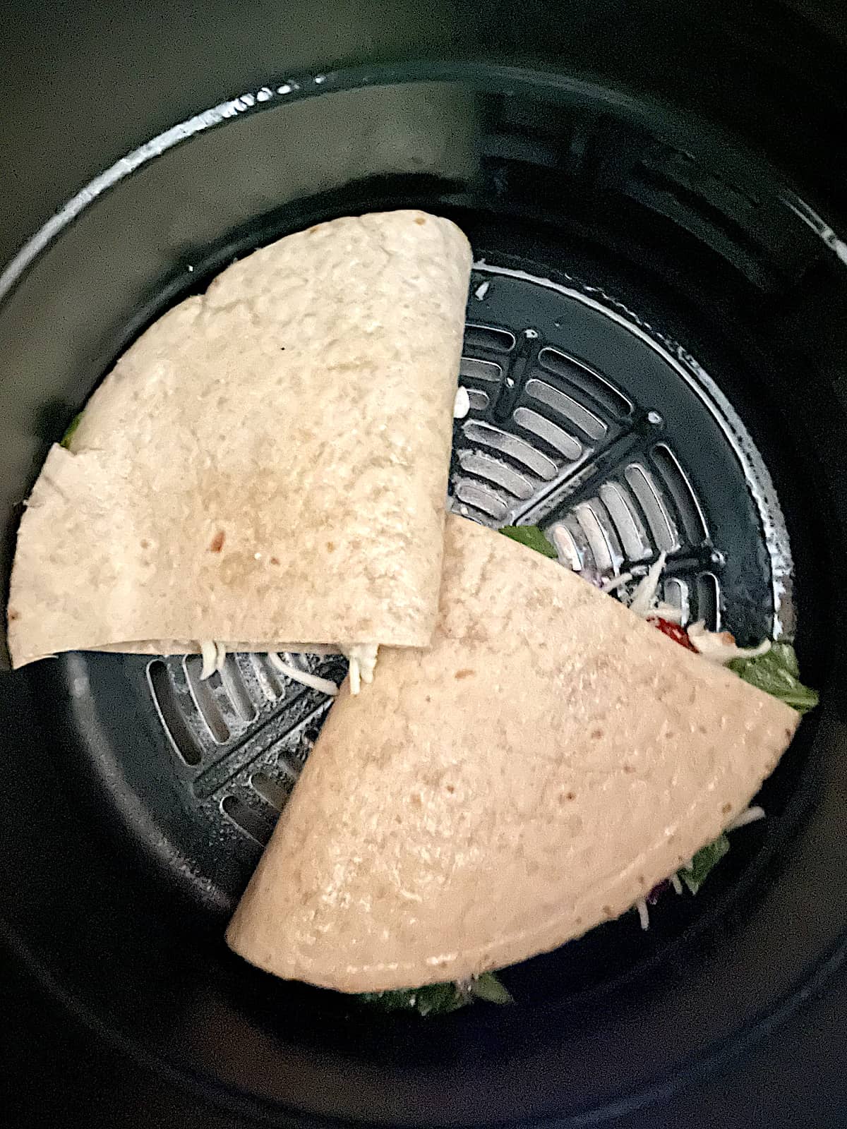 a quesadilla cut into 2 in the air fryer basket