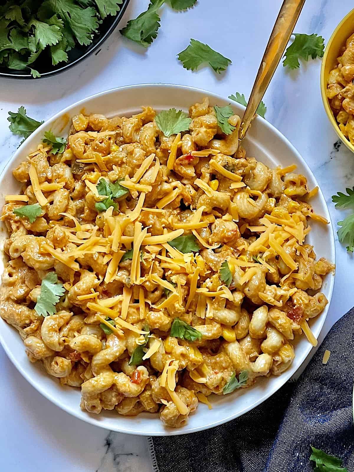 Instant Pot chicken taco pasta on a white plate topped with cilantro and cheddar cheese