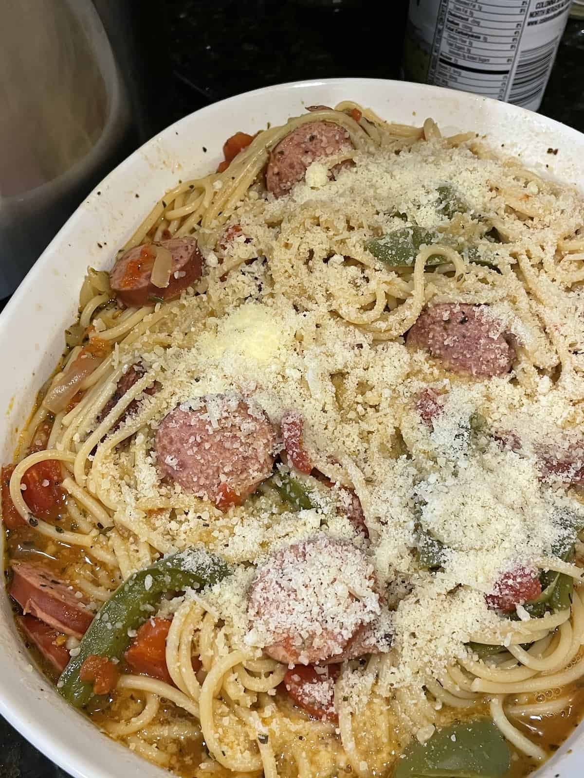 kielbasa pasta topped with parmesan cheese in a serving bowl