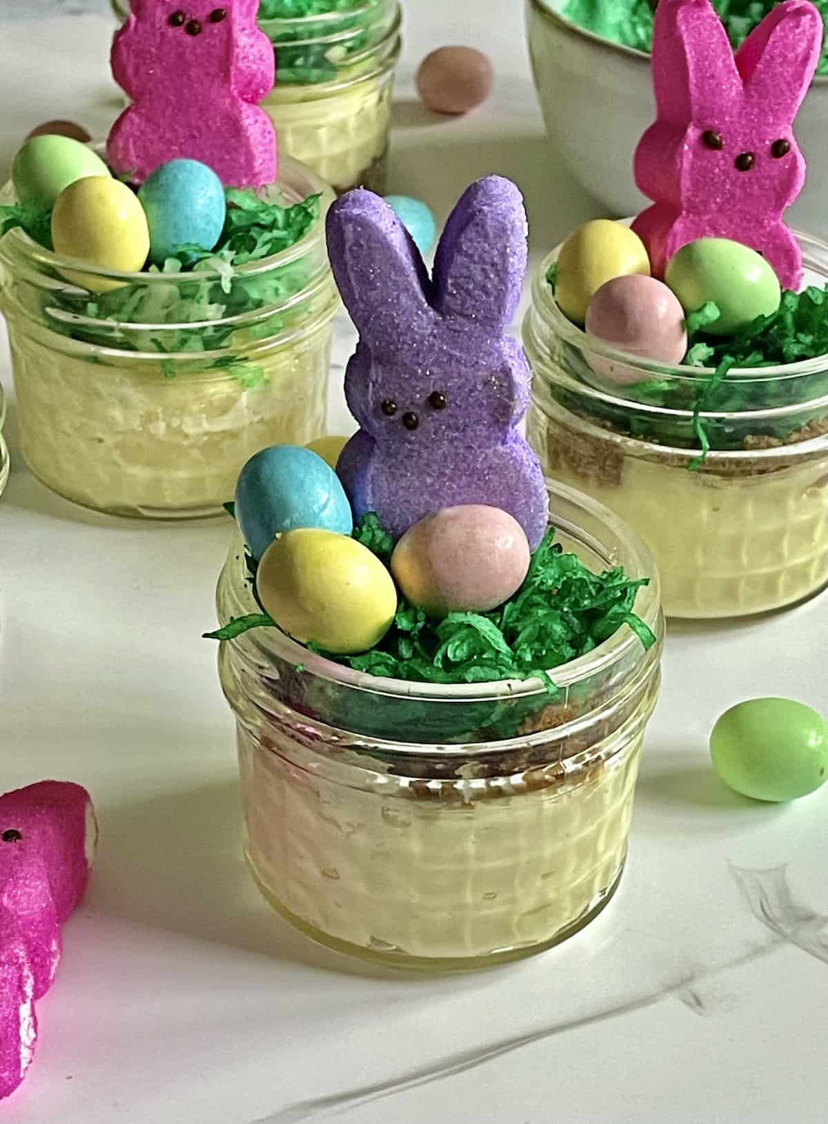 closeup of a mini Easter cheesecake with chocolate eggs and a bunny peep in a mason jar