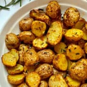 air fryer baby potatoes with rosemary and spices in a white bowl